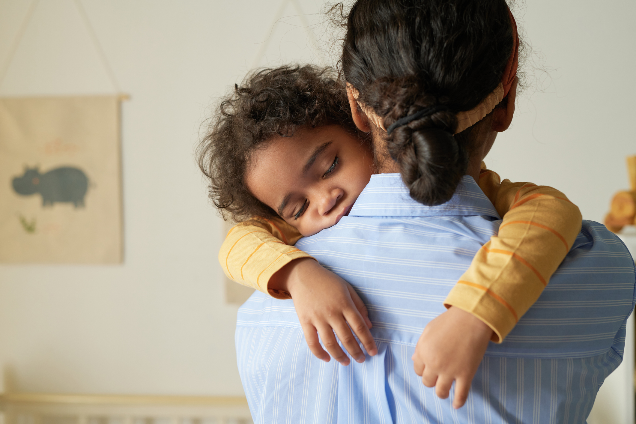 Back view of African American woman holding sleeping child 