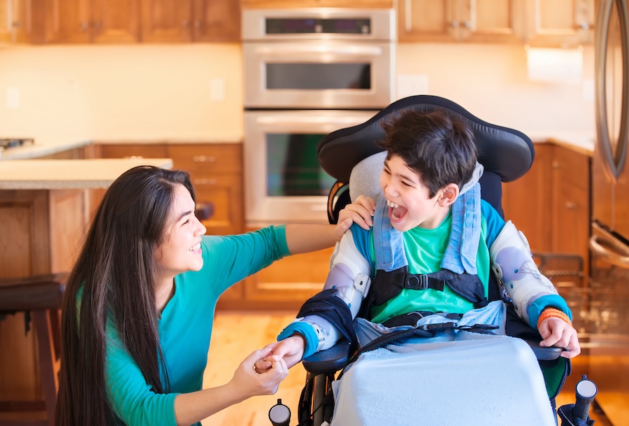 Nine year old disabled boy in wheelchair laughing with caregiver