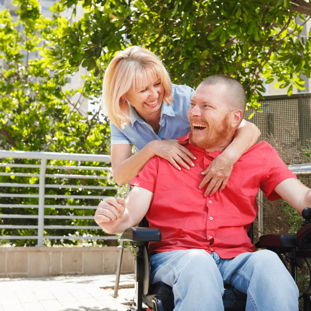 A woman and adult man in a wheelchair happy
