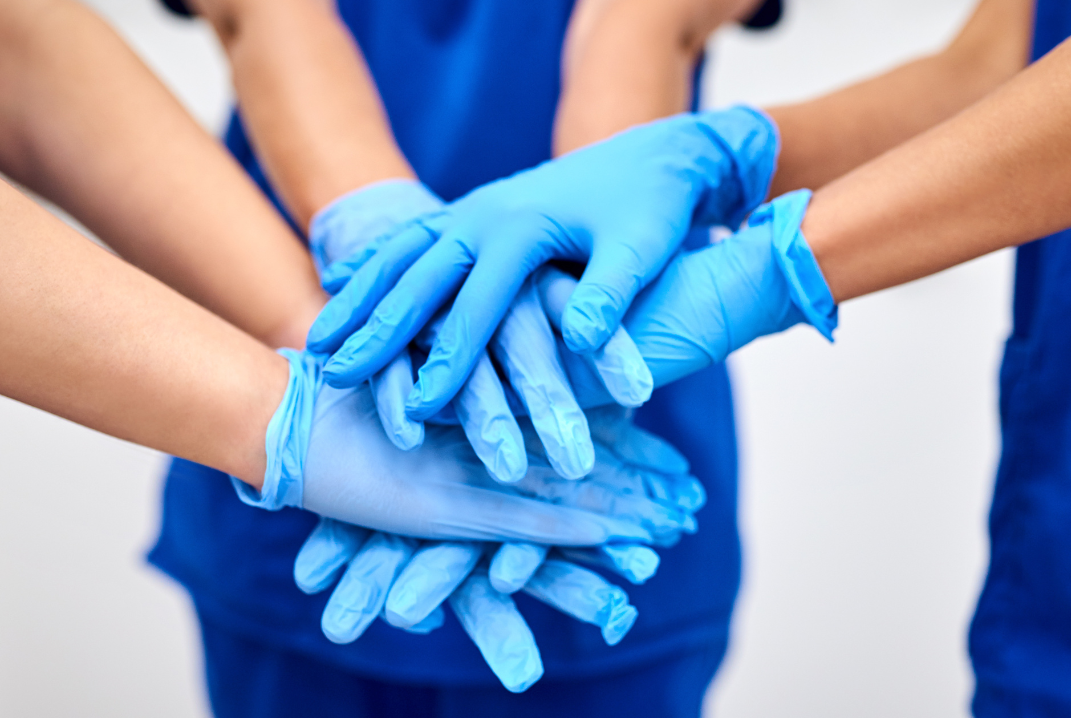 nurse with gloves on putting their hands together