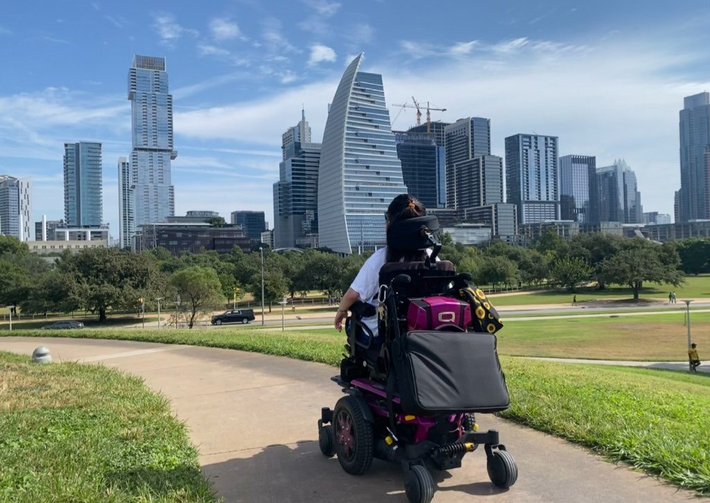 A person driving an electrical wheelchair in a city park