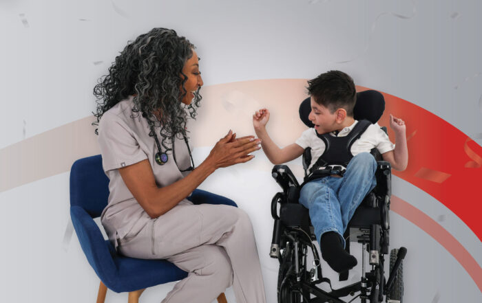 Healthcare professional in scrubs sits with a smiling child in a wheelchair, giving a high-five.