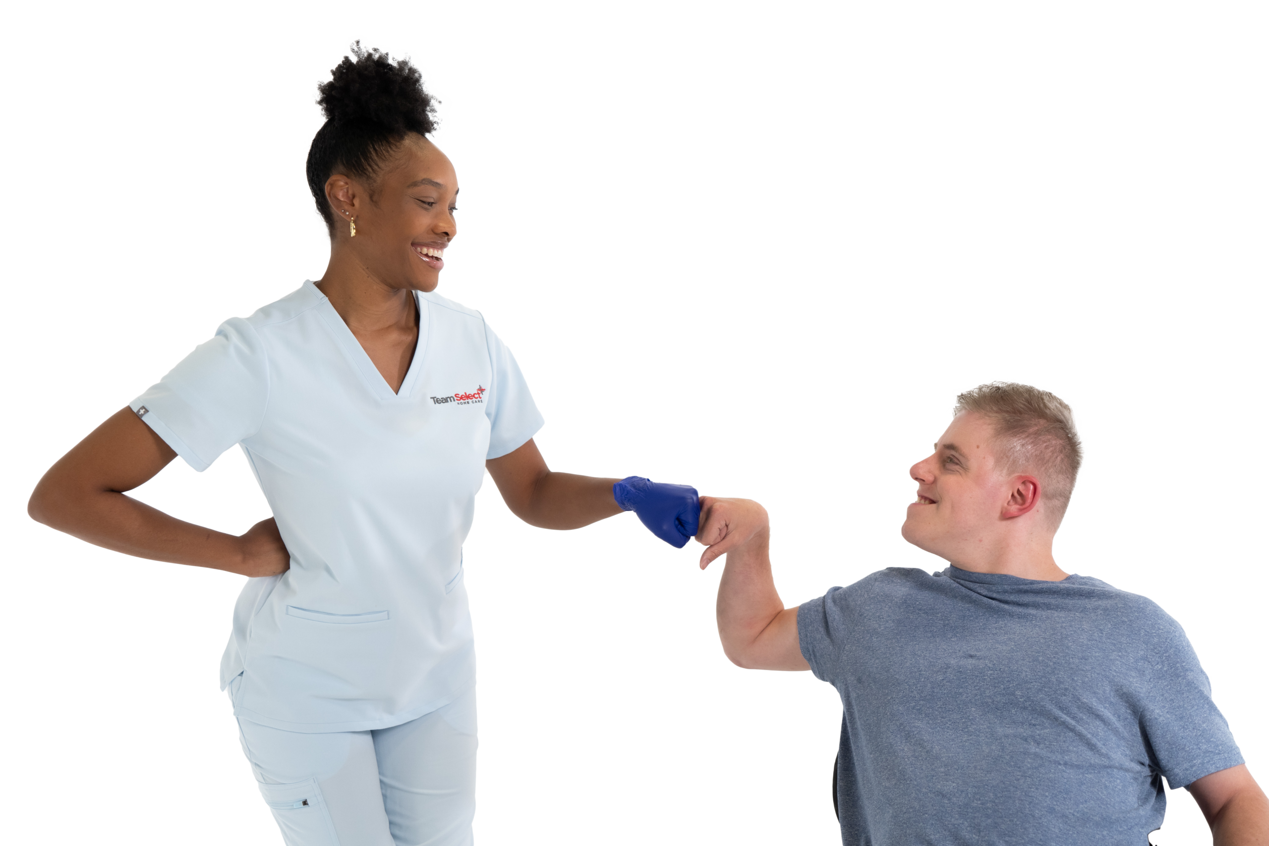 Team_Select_Nurse_and_Patient_Fist-Bumping Female healthcare worker in light blue scrubs fist-bumps with a male patient wearing a gray shirt, both smiling and facing each other.
